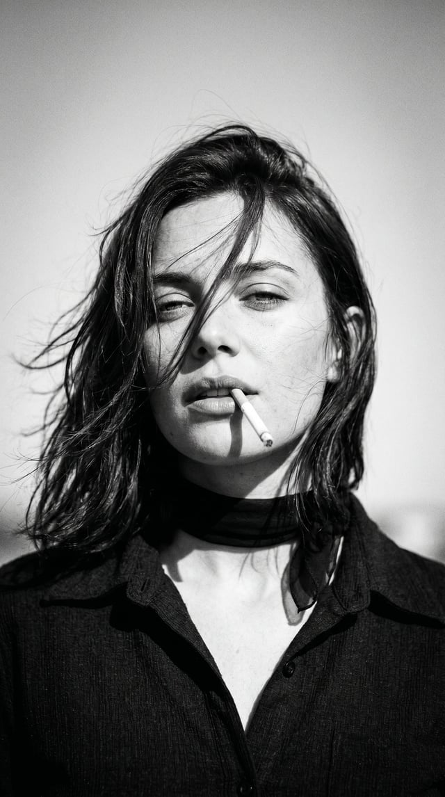 Create a 1970s black-and-white close-up portrait in a windswept outdoor setting, black and white noi