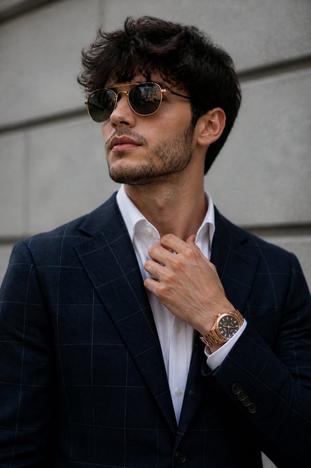 A young man with dark, textured hair and light stubble is captured in a medium shot, adjusting his c