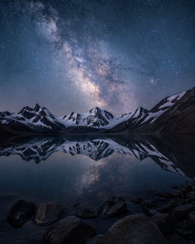 Create a breathtaking realistic landscape photograph of a Milky Way galaxy arching over a dramatic a