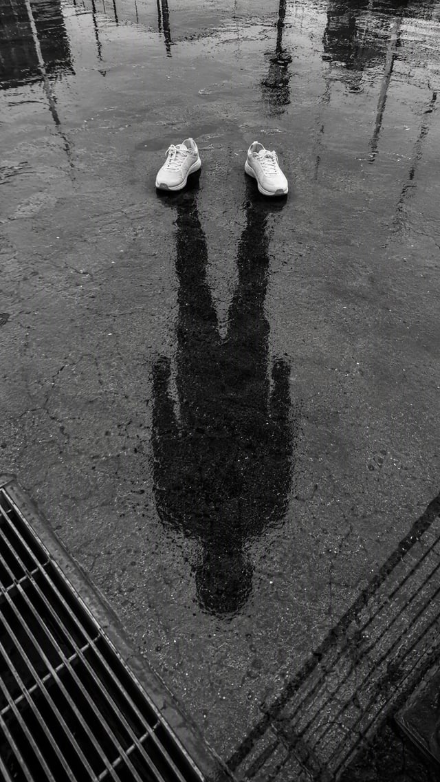 Create an ultra-realistic conceptual street photograph of a pair of white running sneakers standing 