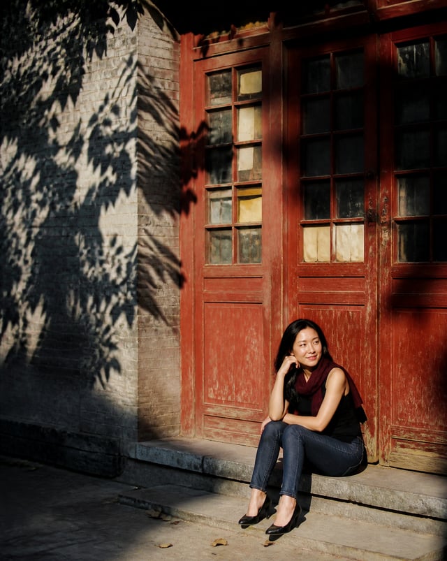 Create a realistic vertical 4:5 candid street portrait sitting casually on a shallow stone step in f