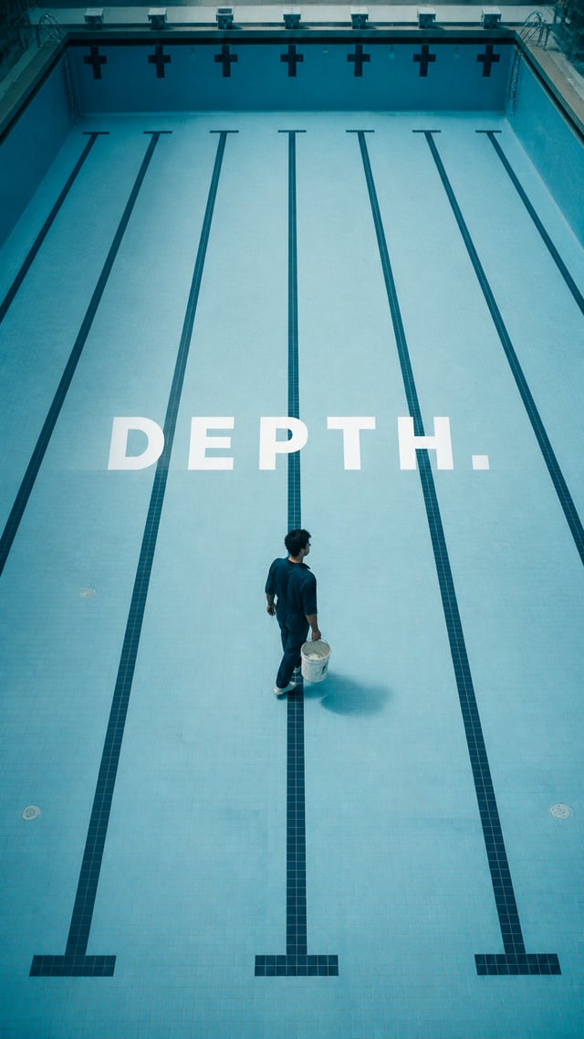 Premium editorial campaign.Main Subject: Young man inside an empty indoor swimming pool during maint