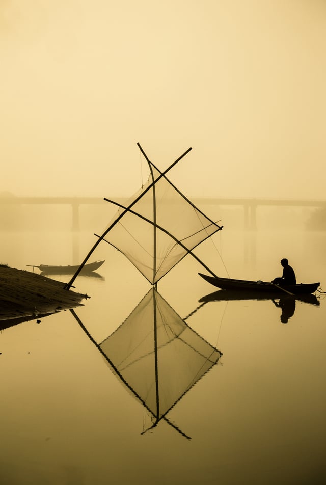 A tranquil river landscape engulfed in a thick, monochromatic golden mist. A large, translucent dip 