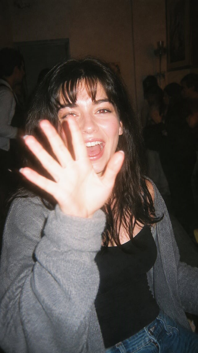 Raw disposable-camera photograph of a clearly adult woman in her mid-20s caught unexpectedly at a ho