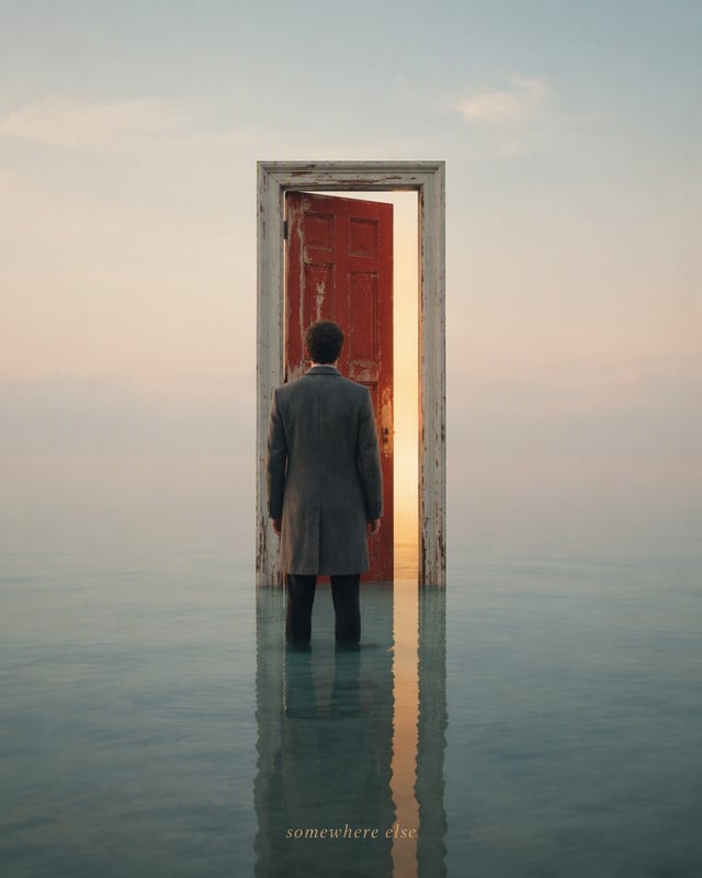 Surreal minimal photograph. A lone weathered red wooden door with its white frame stands upright in 