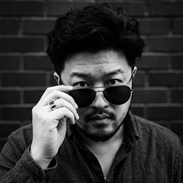 [UPLOAD YOUR IMAGE] A close-up, high-contrast black and white portrait of a man looking directly int