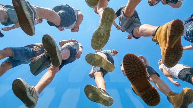 View from under a plane of completely transparent plexiglass. We are looking straight up. Many peopl