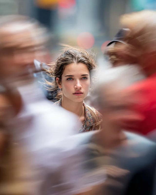 Model looking at camera, close up of face, busy New York street, motion blurred people crossing fram