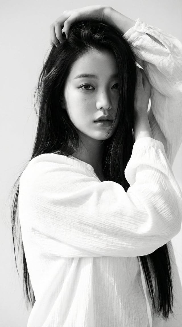 Black-and-white portrait of a young woman with long straight dark hair, wearing a loose white blouse