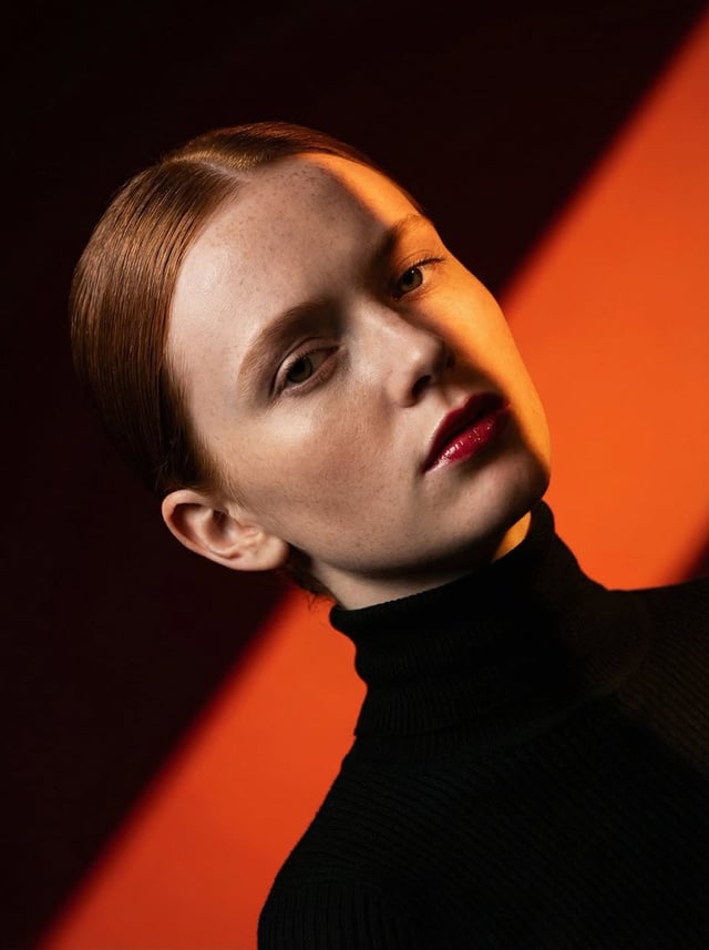 Ultra-high-fashion editorial beauty portrait of a fair-skinned female model with sleek center-parted