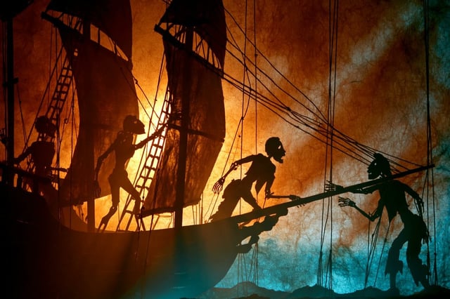 A theatrical shadow puppet scene of a [Subject], shown in stark silhouette against a glowing parchme