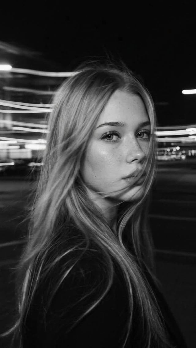 Ultra-realistic black-and-white cinematic street portrait of a beautiful young woman with long flowi