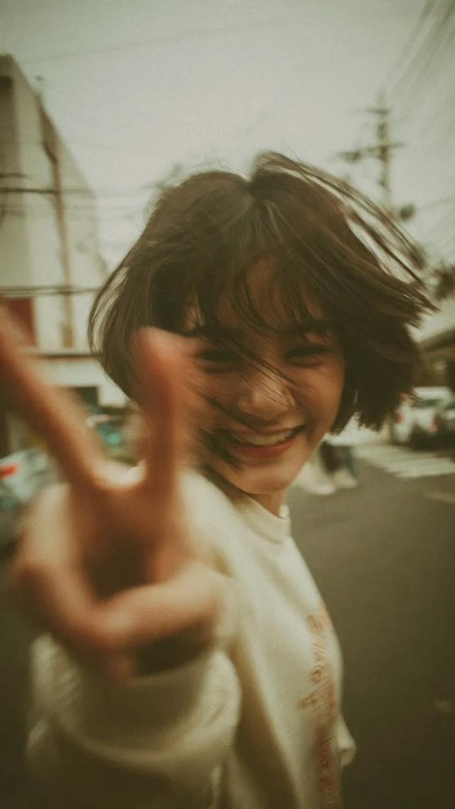 A candid Y2K street photography portrait of a cheerful young woman with a short messy bob haircut, l