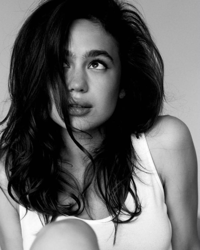 Ultra-realistic black-and-white editorial fashion portrait of a young woman with long, voluminous da