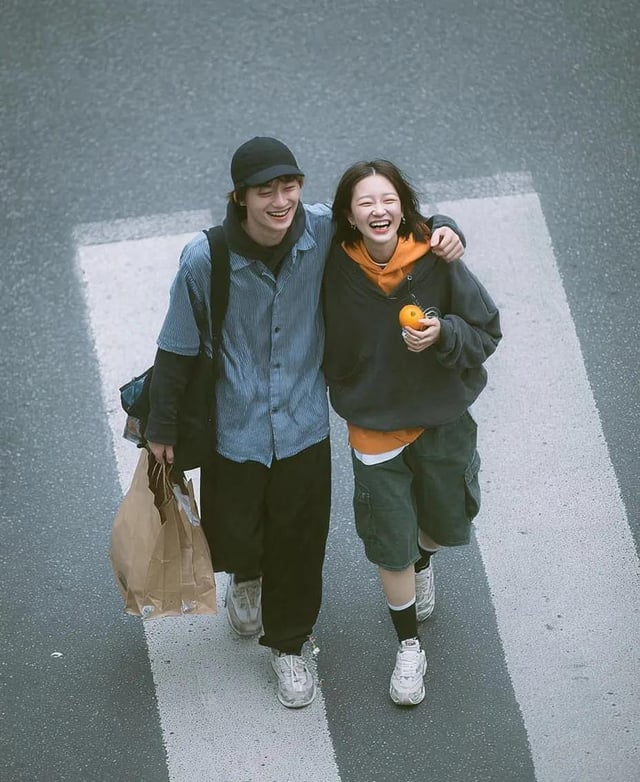 A cinematic overhead street photo of a young couple walking on a zebra crossing, candid and natural 