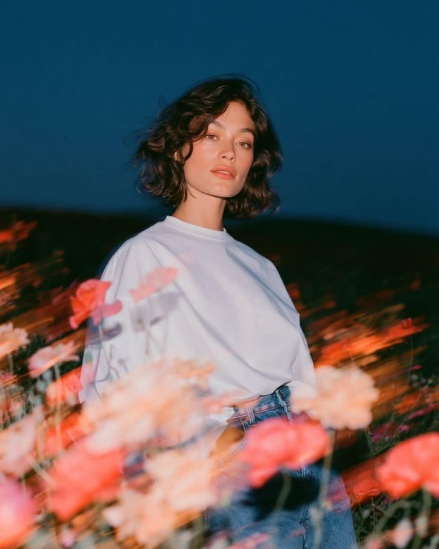 Create a cinematic fashion editorial portrait at blue hour in an open wildflower field. A beautiful 