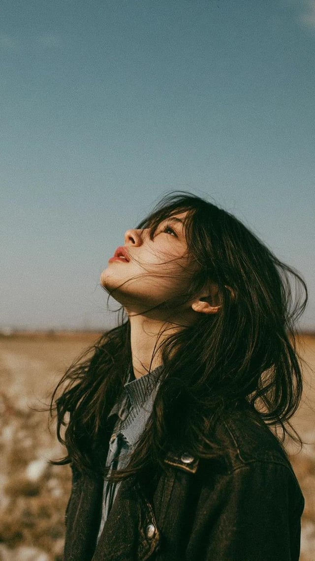 Cinematic minimalist portrait of a beautiful young East Asian woman standing alone in an open wildfl