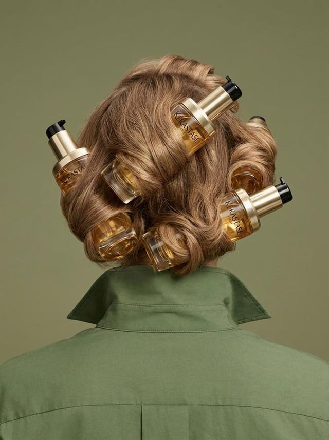 Studio product photo shot from behind of a person with light brown wavy/curled hair styled 