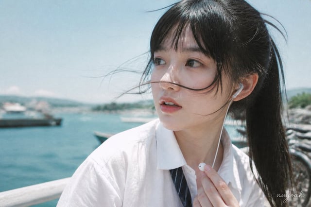 用途：photorealistic-natural，延续盛夏海港放学漫游写真摄影方案。图片 1 是本张主摄影参考，负责海港强风中的横向面部近景、碎发横穿五官、偏青天空与水面、自然皮肤和低商业抛光的旧数