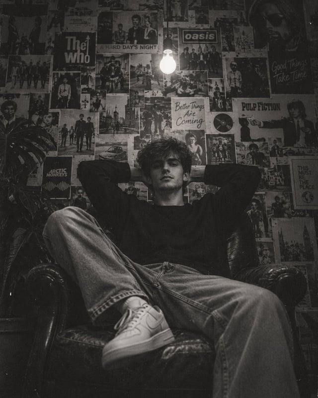 Create an ultra-realistic cinematic black-and-white editorial photograph of a young man relaxing dee